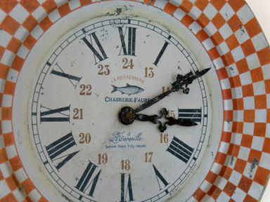 A clock face with Roman numerals and a checkered orange and white border at Portside in Seahouses