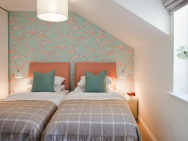 A bedroom with two single beds with green pillows and checkered blankets at Portside in Seahouses