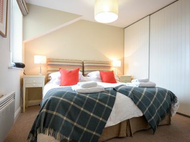 A bedroom with a double bed two bedside tables with lamps and a large wardrobe at Portside in Seahouses