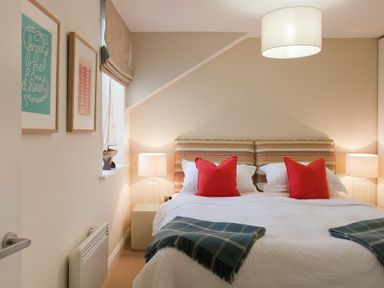 A bedroom with a double bed and red pillows at Portside in Seahouses
