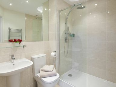 A bathroom with a pedestal sink a toilet with towels on top and a shower enclosure at Portside in Seahouses