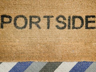 A doormat with the word Portside on a striped carpet