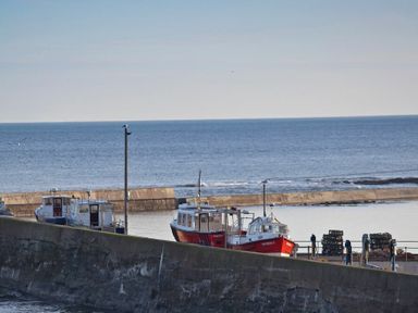 Boats docked behind a concrete breakwater at Portside in Seahouses