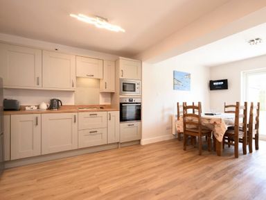 A kitchen with cabinets and appliances next to a dining table with chairs at Anchor Lodge in Seahouses