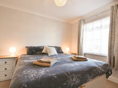 A bedroom with a double bed two bedside tables with lamps and a window with curtains at Anchor Lodge in Seahouses