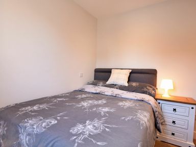 A bedroom with a bed with floral bedding a pillow and a bedside table with a lamp at Anchor Lodge in Seahouses