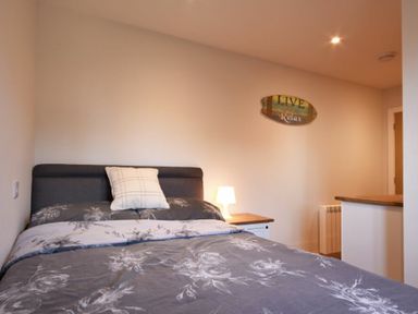 A bedroom with a bed a pillow a bedside table with a lamp and a wall decoration at Anchor Lodge in Seahouses