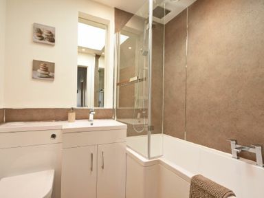 A bathroom with a toilet sink cabinet bathtub shower and a brown towel at Anchor Lodge in Seahouses
