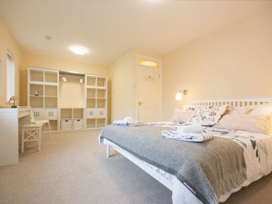 A bedroom with a bed a shelving unit and a small desk at Summerfold in Warkworth