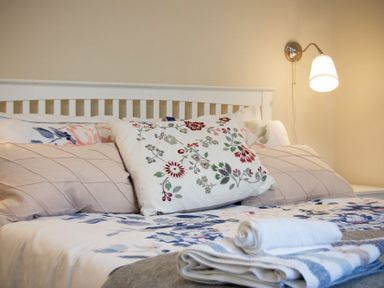 A bed with floral and patterned pillows and neatly folded towels on the blanket at Summerfold in Warkworth