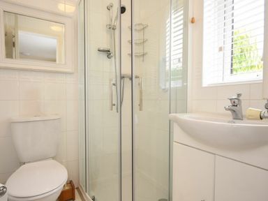 A bathroom with a toilet a shower enclosure and a sink under a window at Summerfold in Warkworth