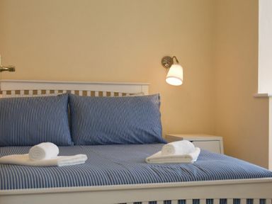 A bedroom with a white bed and blue striped bedding with towels on the bed at Summerfold in Warkworth
