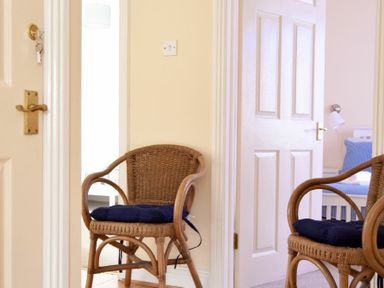 A hallway with wicker chairs facing each other and open doors leading to other rooms at Summerfold in Warkworth
