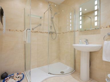 A bathroom with a glass shower enclosure a white pedestal sink and a mirror at Summerfold in Warkworth
