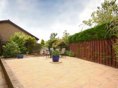 A patio with a table and chairs surrounded by plants and a wooden fence at Summerfold in Warkworth