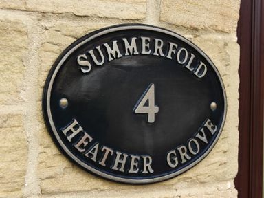 A house number plaque with the text Summerfold 4 Heather Grove on a stone wall at Summerfold in Warkworth