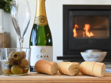 A bottle of cava with two champagne glasses a bowl of olives and three pieces of bread in front of a fireplace at Waters Edge Beadnell Harbour Road in Beadnell