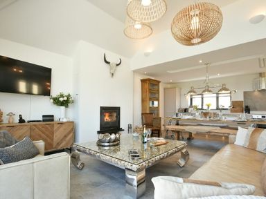 A living room with a fireplace television and dining area at Waters Edge Beadnell Harbour Road in Beadnell