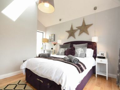 A bedroom with a bed with gray and white pillows and two star decorations on the wall at Waters Edge Beadnell Harbour Road in Beadnell