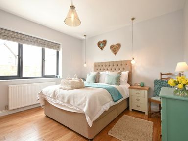 A bedroom with a bed a side table a chair and a chest of drawers at Waters Edge Beadnell Harbour Road in Beadnell