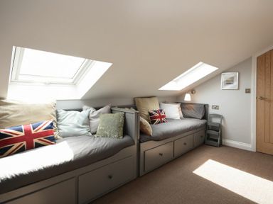 A room with two gray bench seats under skylight windows with cushions including Union Jack pillows at Waters Edge Beadnell Harbour Road in Beadnell