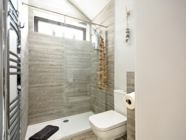 A bathroom with a walk in shower and a toilet at Waters Edge Beadnell (Harbour Road) in Beadnell