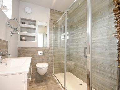 A bathroom with a wall-mounted toilet sink and a glass shower enclosure at Waters Edge Beadnell Harbour Road in Beadnell