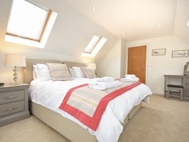 A bedroom with a double bed bedside tables lamps and a desk with a chair at Portland Beadnell
