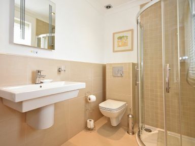A bathroom with a wall-mounted sink toilet and glass shower enclosure at Portland in Beadnell