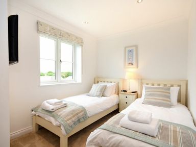 A bedroom with two single beds a nightstand between them and a wall-mounted television at Portland in Beadnell