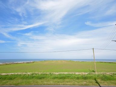 A grassy field with power lines and the sea in the background in Portland Beadnell