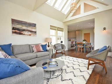 A living room with sofas chairs and a coffee table next to a dining area at South View nr Bamburgh in Seahouses
