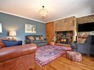 A living room with sofas a wood burning stove and a patterned rug at South View nr Bamburgh in Seahouses