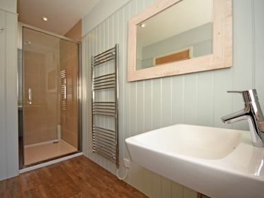 A bathroom with a shower enclosure a towel radiator a mirror and a sink at South View nr Bamburgh in Seahouses