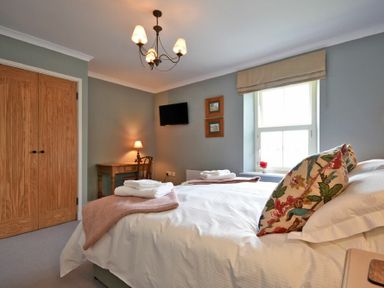 A bedroom with a double bed towels on bed wooden desk with chair and wall mounted tv at South View nr Bamburgh in Seahouses