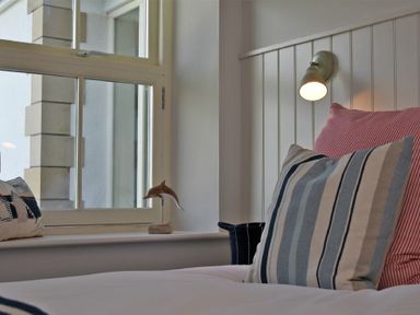 A bedroom with pillows on a bed and a window with a dolphin decoration at South View nr Bamburgh in Seahouses