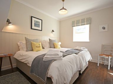 A bedroom with two beds bedside table chair and window at South View nr Bamburgh in Seahouses