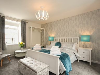 A bedroom with a bed bedside tables lamps and a seating bench at Rivershield in Warkworth