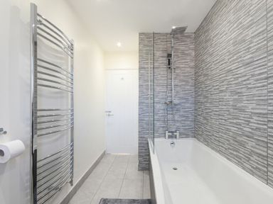 A bathroom with a bathtub shower combination and a wall-mounted towel radiator at Rivershield in Warkworth