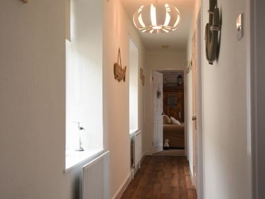A hallway with wooden floor a white radiator and a window with a sculpture on the sill at Rivershield in Warkworth