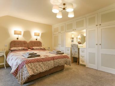 A bedroom with a double bed bedside tables built-in wardrobes and a dressing table at The Lodge Elsdon