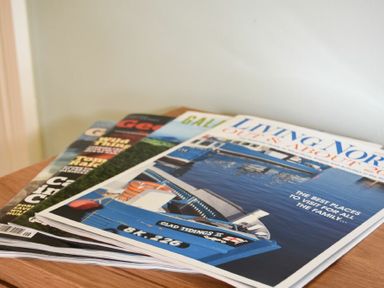 A stack of magazines on a wooden surface showing a boat on water on the top magazine at Rose Cottage Elsdon