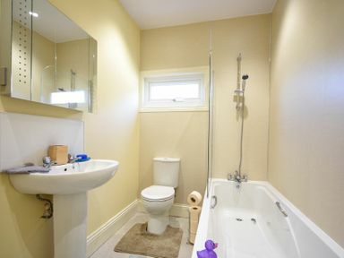A bathroom with a pedestal sink toilet bathtub showerhead and a small window at Rose Cottage Elsdon