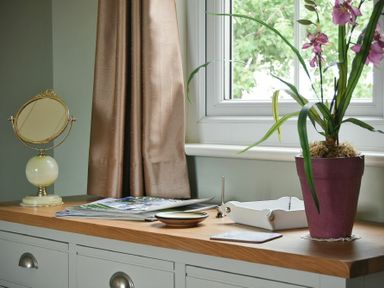 A windowsill with a potted plant a mirror magazines and small trays at Rose Cottage Elsdon