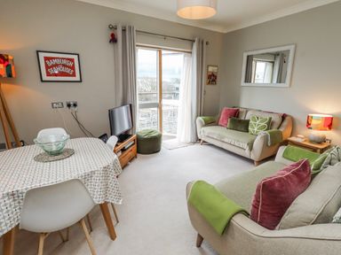 A living room with a sofa and dining table at Cuddy's Holm in Seahouses