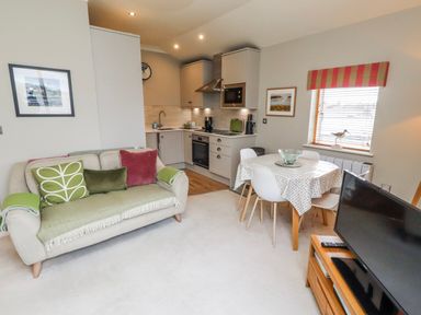 A living room with a sofa and dining area at Cuddy's Holm in Seahouses