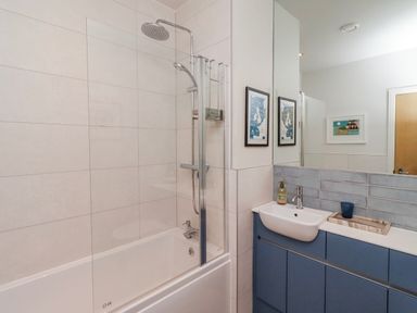 A bathroom with a bathtub, shower, and sink at Cuddy's Holm in Seahouses