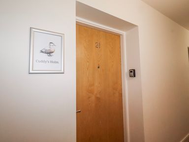 A door with number 21 and a framed picture at Cuddy's Holm in Seahouses