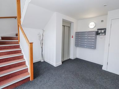 A hallway with a staircase and mailbox units at Cuddy's Holm in Seahouses