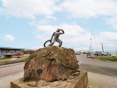 A statue on a rock near a road at Cuddy's Holm in Seahouses